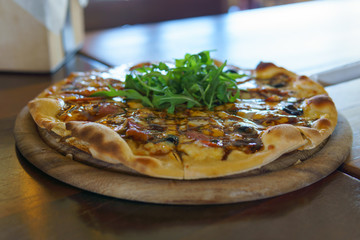 close up of delicious bacon and cheese pizza on wooden plate. italian style.