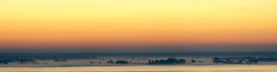 panorama of the big lake in the morning, trees in the fog