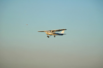 white single engine plane landing while yellow plane awaits