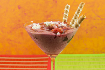 Una copa con helado de fresa hecho en casa decorado con fresas nata y barquillos