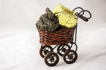 antique looking baby stroller with large gold foil wrapped present isolated on white background