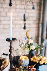 decorated plates with boards of cheese, baskets of bread, candles, candlesticks, flowers, bouquet, jam.