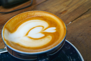 close up ,top view of hot latte in dark blue cup with spoon on the wooden table. copy space for your text.