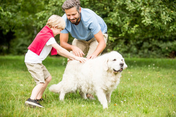 Vater und Sohn spielen mit Hund