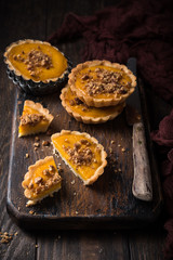 Pumpkin mini pie, tartlet made for Thanksgiving day on old wooden background. Healthy autumn food concept with copy space. Dark photo.