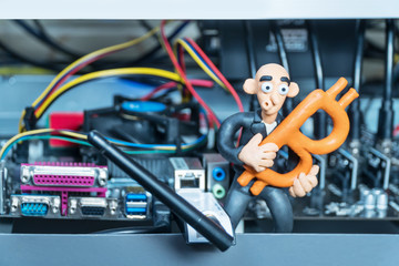 Fototapeta premium Bald plasticine man with a pickaxe in his hand sitting on the computer for mining cryptocurrency