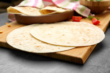Wooden board with delicious tortillas on kitchen table