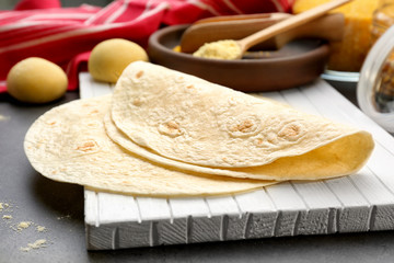 Wooden board with delicious tortillas on kitchen table