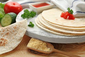 Wooden board with delicious tortillas on kitchen table