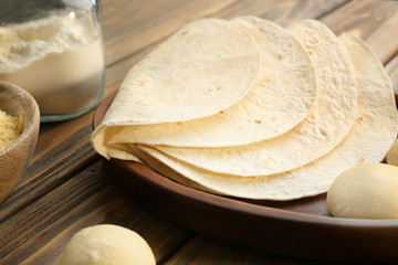 Delicious tortillas and dough balls on kitchen table