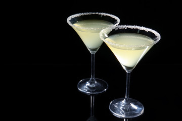 Glasses of lemon drop martini on black background
