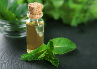 Bottle of essential oil and mint on table