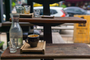 close up of empty espresso coffee in dark blue cup with water in transparent glass in the wooden plate on the stairs.