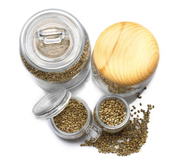 Glass jars with hemp seeds on white background