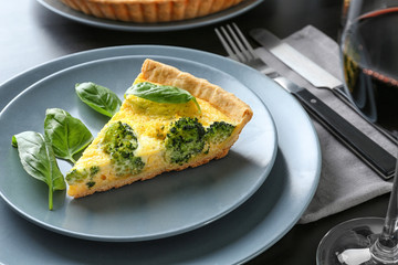 Plate with piece of tasty broccoli quiche on table