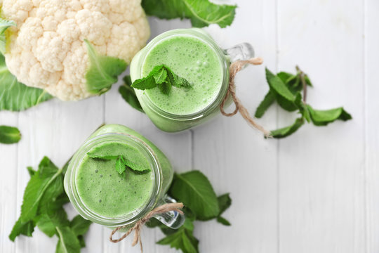 Healthy smoothie with kale in mason jars on wooden table
