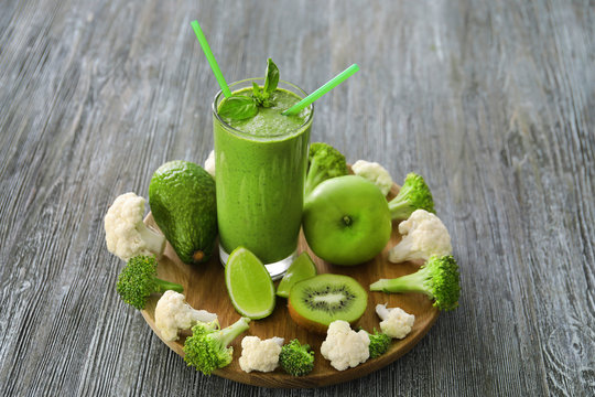 Healthy smoothie with kale in glass on wooden board
