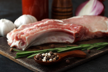 A raw piece of pork steak with rosemary, garlic, onion and pepper