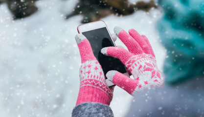 Woman using smartphone in winter with gloves for touch screens