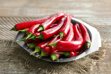Plate with red chili peppers on wooden table