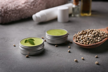 Jars with hemp lotion on grey background