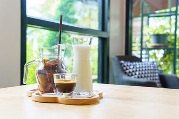 iced cube coffee latte with milk and shot of espresso on the wooden table in the cafe with copy space for text.