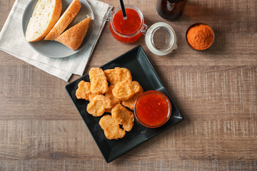 Composition with chicken nuggets and chili sauce on kitchen table