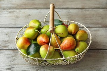 Ripe pears in metal basket on wooden table