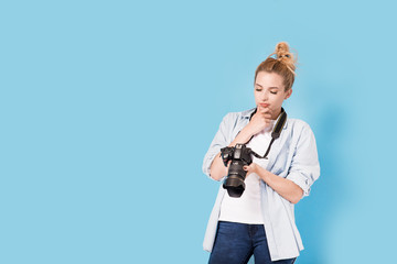 Young blonde photographer holds looks at the photo she made and thinks