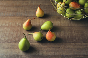 Fototapeta na wymiar Ripe pears and metal fruit bowl on wooden table