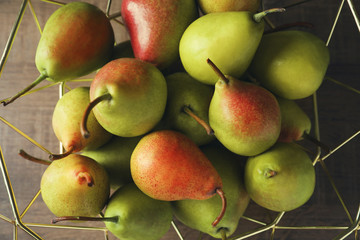 Ripe pears in metal fruit bowl on wooden table, closeup