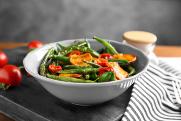 Bowl with delicious green beans, pepper and carrot slices on table