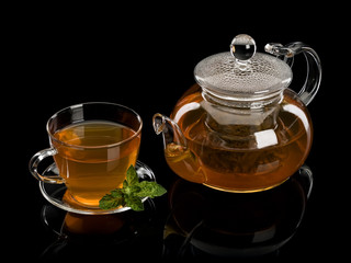 Fresh mint and green tea in a cup and a teapot from glass