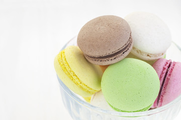 Variety of macaroons in a bowl on a white wooden table