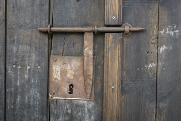 Closeup vintage door lock of external antique wooden door with a door pin lock, weathered on a Country house