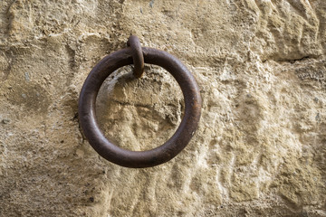 old iron ring a little rusty embedded in a stone wall, used to leave tethered animals like horses or mules, vintage