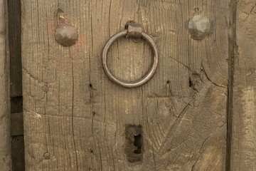 Closeup vintage door lock of external antique wooden door with a door knocker, weathered on a Country house