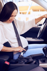 Beautiful pregnant lady fastening car seat belt