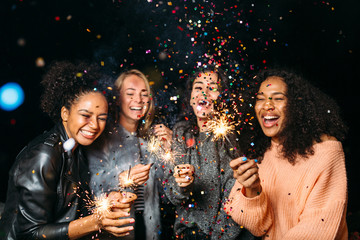 Happy friends. Group of smiling women holding sparklers under confetti 