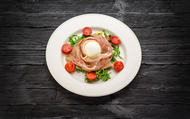 Buffalo mozzarella and prosciutto salad. Dark wooden table.