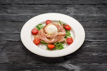 Buffalo mozzarella and prosciutto salad. Dark wooden table.