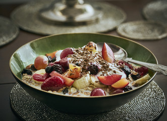 A green bowl of Muesli with mixed, chopped fruit, yogurt and seeds