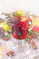 New Year's mulled wine in a glass on the background of twigs, candles and garlands.