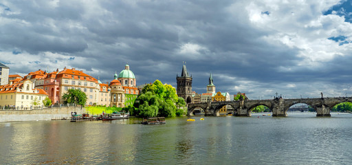 Obraz premium Landscape of the romantic city of Prague under a blue sky. Panoramic view of Charles bridge and old town on a summer day in the capital Czech Republic. Cruise on the Moldovan river.