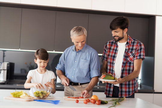 Family cooking salad. A man, his father and his son prepare a salad for Thanksgiving