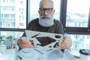 Serious mature architect is looking at pattern