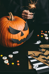 Happy halloween preparation. Halloween pumpkin, sweets, sparkler and halloween cards made of craft paper