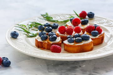 Berry crostini on a white dish.