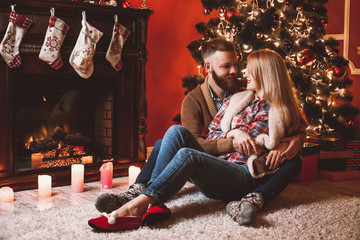 A couple of lovers resting by the fireplace in the Christmas room. Feet in woolen socks warming in winter time.