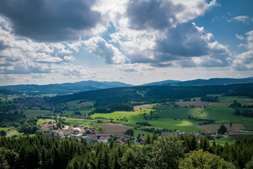 Fototapeta na wymiar Blick in den Bayerischen Wald mit Wolken am Himmel und Sonnenstrahlen und Feldern